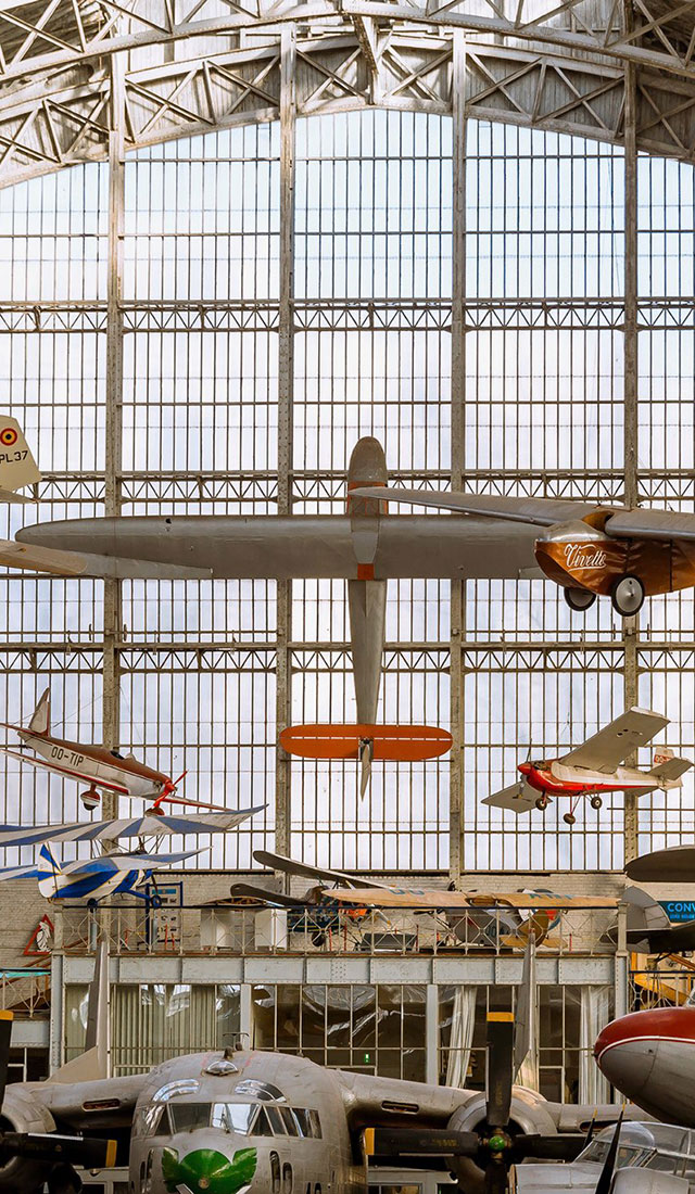 tall aircraft hangar with glass windows full of planes