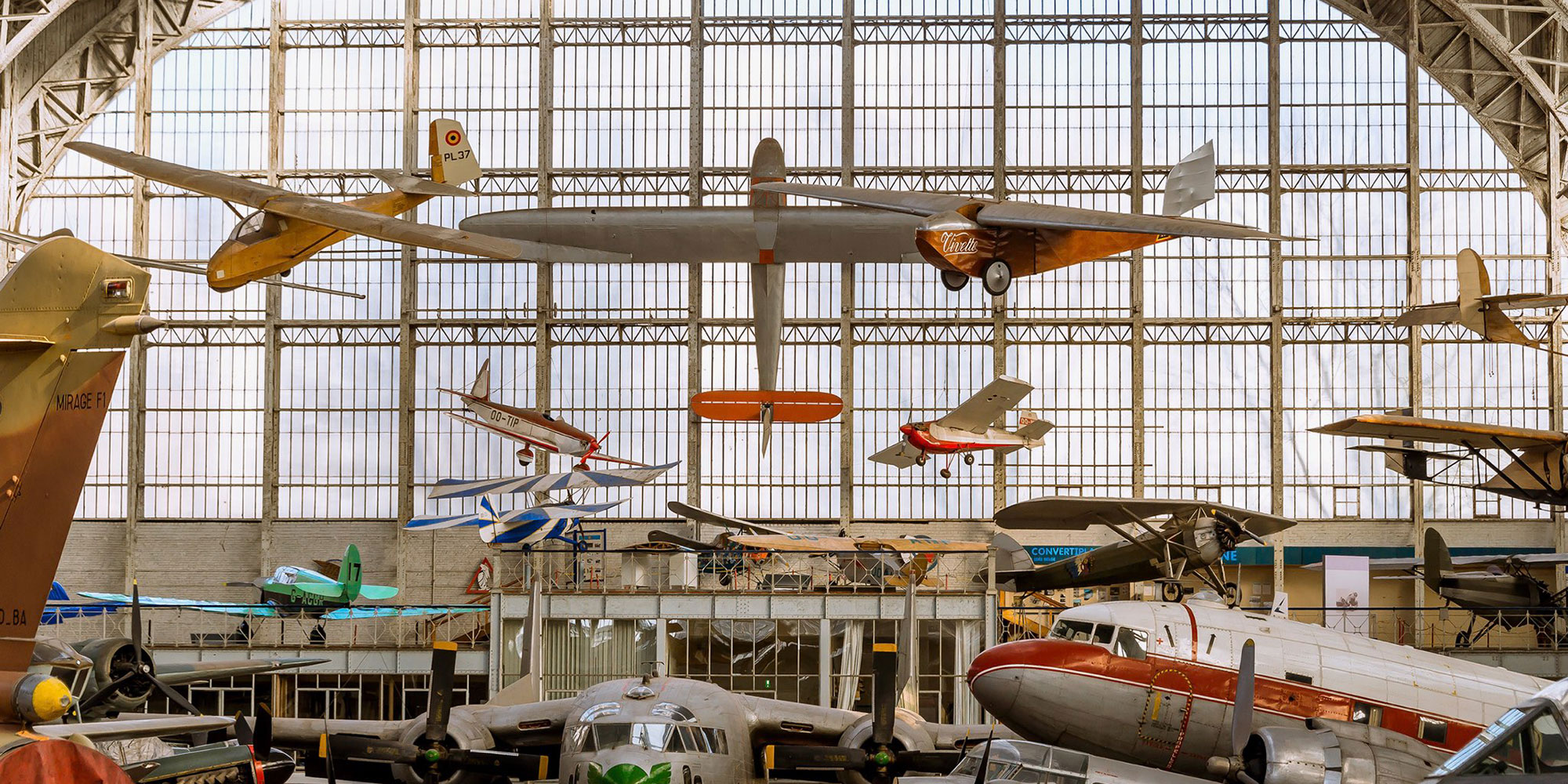 tall aircraft hangar with glass windows full of planes